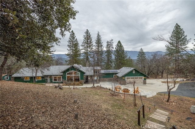 view of front of property with a mountain view, a garage, and solar panels