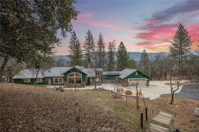 exterior space with a mountain view, a garage, and solar panels