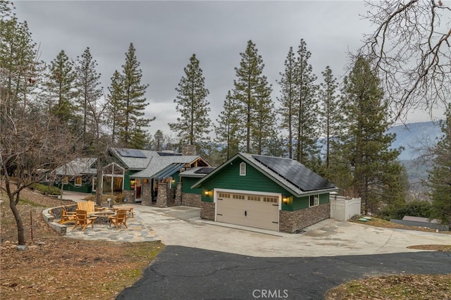 craftsman-style house with a garage, a fire pit, and solar panels