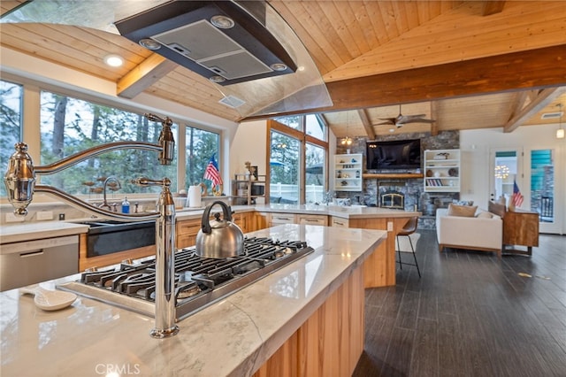 kitchen featuring lofted ceiling with beams, a stone fireplace, wooden ceiling, and light stone counters