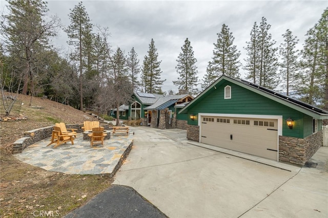 exterior space featuring solar panels, a garage, and a fire pit