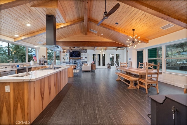 kitchen with island range hood, decorative light fixtures, vaulted ceiling with beams, dark hardwood / wood-style flooring, and a large island with sink