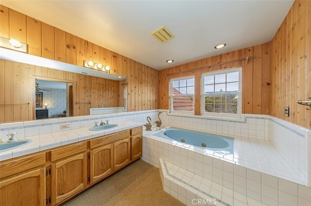 bathroom featuring tiled bath and vanity