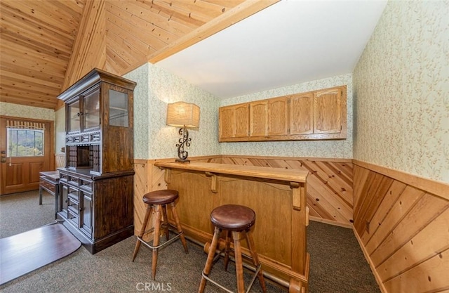 bar with dark carpet, vaulted ceiling, wooden walls, and wooden ceiling