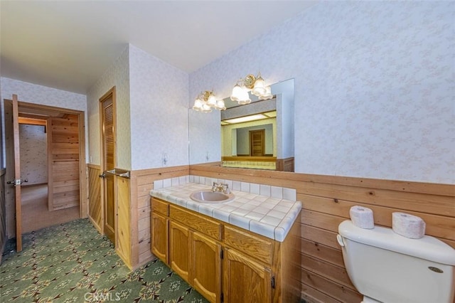 bathroom featuring toilet, vanity, and wooden walls