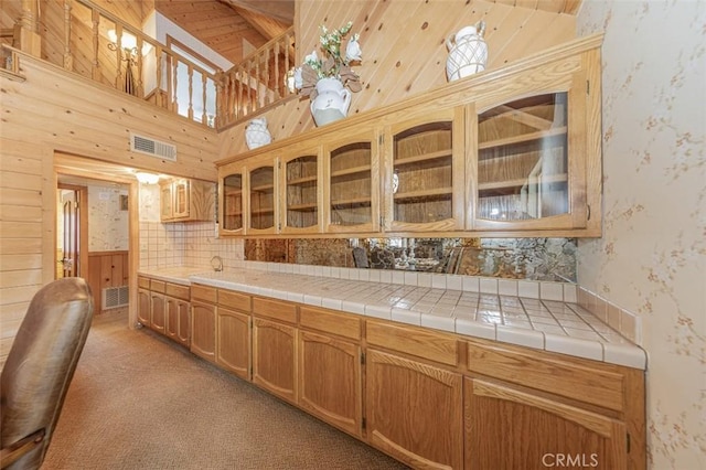 kitchen with sink, tile countertops, wooden walls, and light colored carpet