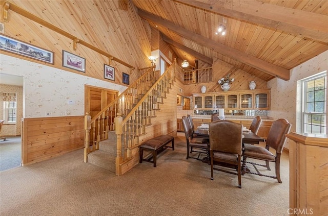 dining room with carpet floors, high vaulted ceiling, wooden walls, wood ceiling, and beam ceiling