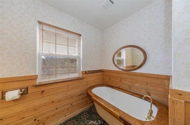 bathroom with wooden walls and a bath