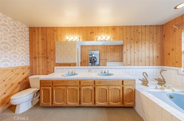 bathroom with vanity, toilet, and a relaxing tiled tub