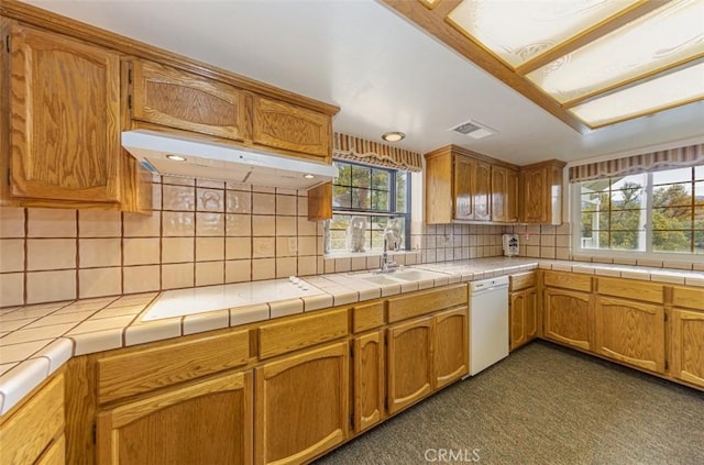 kitchen with stovetop, dishwasher, tile counters, backsplash, and sink