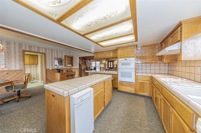 kitchen with dark carpet, white appliances, tile counters, and a center island