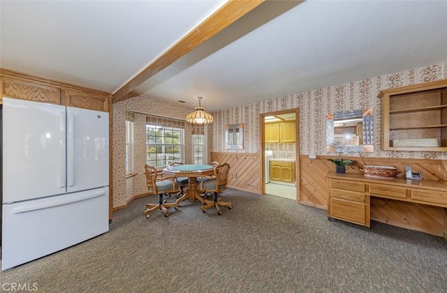 carpeted dining area with beam ceiling and washer / clothes dryer