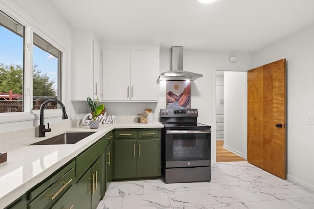 kitchen with electric stove, sink, green cabinets, white cabinetry, and wall chimney exhaust hood