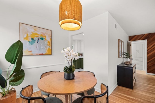 dining area featuring light hardwood / wood-style flooring and wooden walls