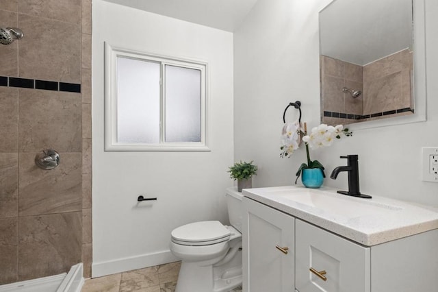 bathroom with vanity, toilet, and a tile shower