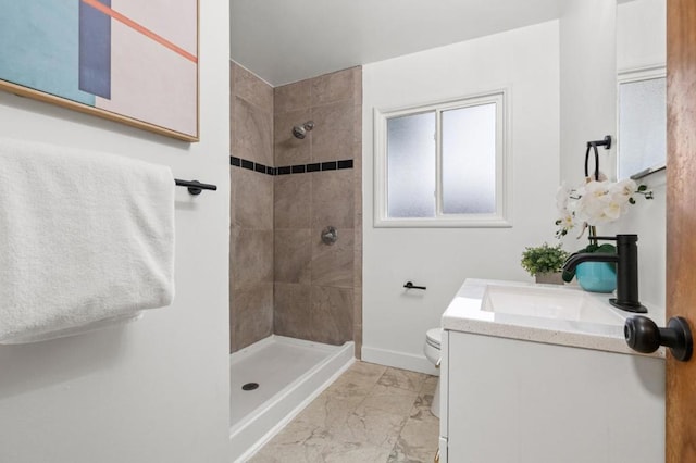 bathroom with vanity, tiled shower, and toilet