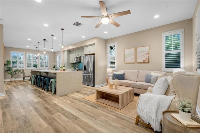 living room with ceiling fan and light hardwood / wood-style flooring