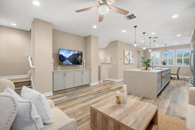 living room featuring ceiling fan, sink, and light wood-type flooring