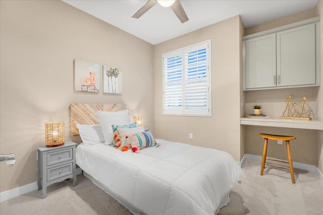 bedroom with ceiling fan, light colored carpet, and built in desk