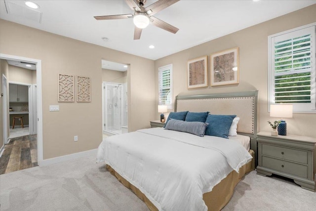 bedroom featuring light colored carpet, ceiling fan, and ensuite bathroom