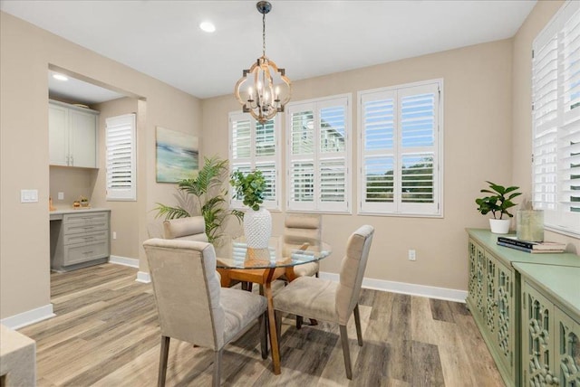 dining room featuring a chandelier, built in desk, and light hardwood / wood-style floors