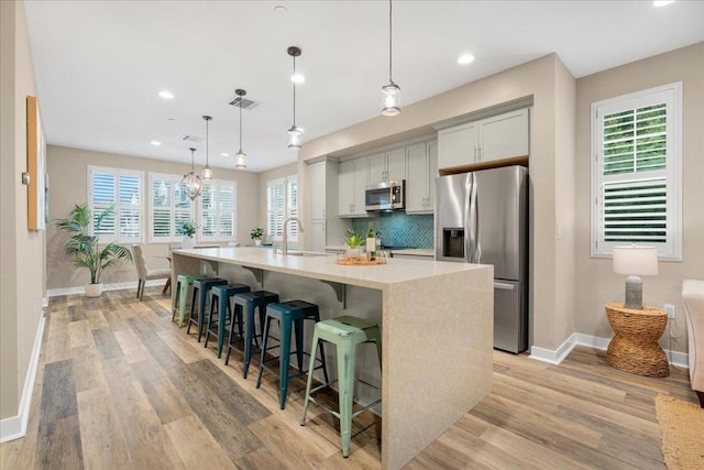 kitchen with a spacious island, a breakfast bar, tasteful backsplash, decorative light fixtures, and stainless steel appliances