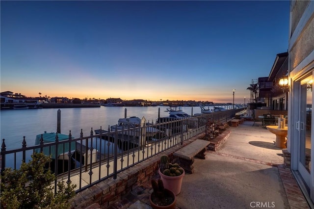 patio terrace at dusk with a water view and a boat dock