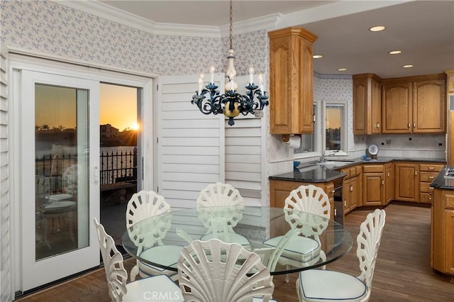 dining room with dark hardwood / wood-style flooring, sink, crown molding, and a chandelier