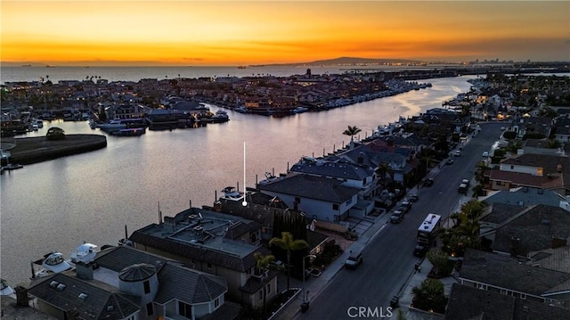 aerial view at dusk featuring a water view