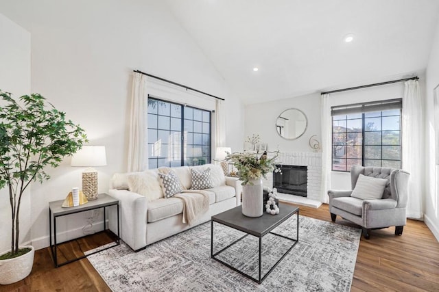 living room featuring a brick fireplace, hardwood / wood-style flooring, and high vaulted ceiling