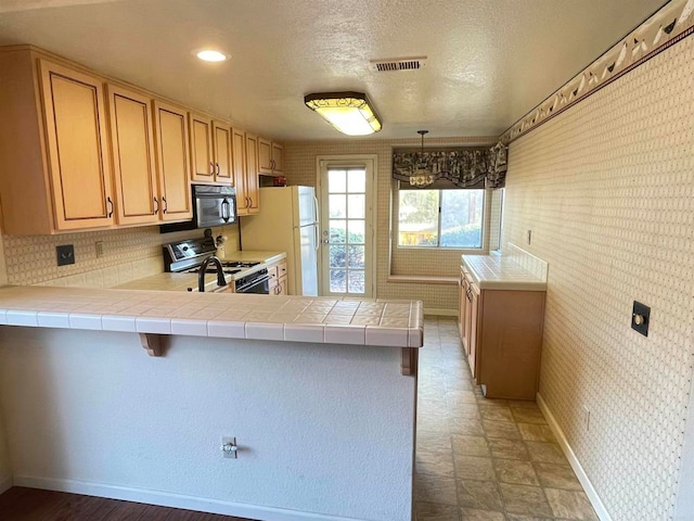 kitchen featuring decorative light fixtures, tile countertops, white appliances, and kitchen peninsula