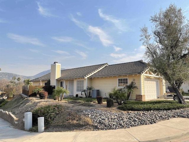 single story home featuring cooling unit, a garage, and a mountain view