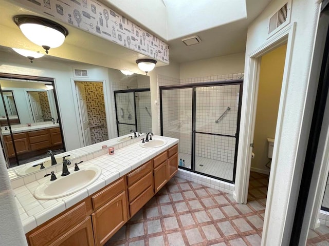 bathroom with vanity, toilet, and a shower with door