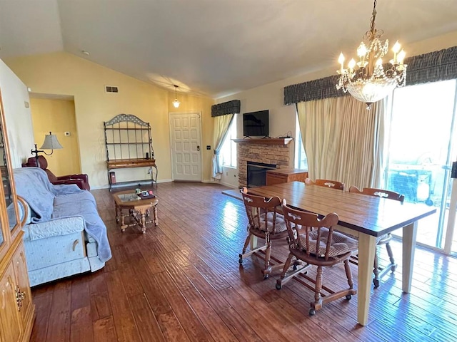 dining room featuring lofted ceiling, a fireplace, hardwood / wood-style floors, and a notable chandelier