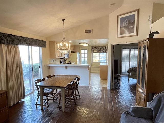 dining space with an inviting chandelier, lofted ceiling, and dark hardwood / wood-style floors