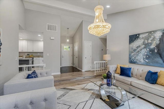 living room featuring beamed ceiling, wood-type flooring, an inviting chandelier, and high vaulted ceiling