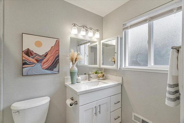 bathroom with vanity, toilet, and a wealth of natural light