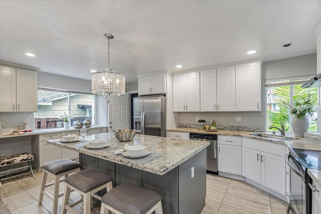 kitchen with sink, appliances with stainless steel finishes, hanging light fixtures, a kitchen island, and a kitchen bar