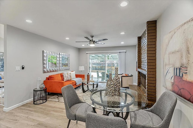 dining space featuring ceiling fan, a fireplace, and light hardwood / wood-style floors