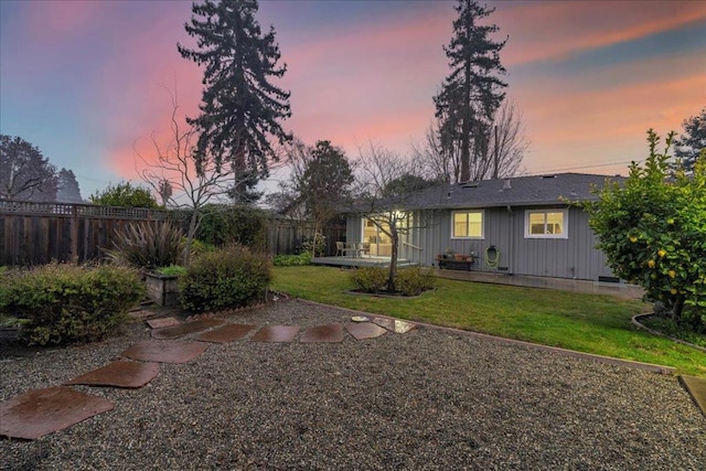 back house at dusk with a yard and a patio area