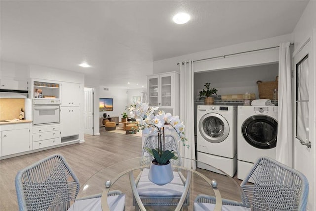 laundry room with light hardwood / wood-style flooring and washing machine and dryer