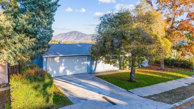 view of front of house with a garage, a mountain view, and a front yard