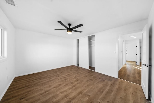 unfurnished bedroom with a closet, dark hardwood / wood-style floors, and ceiling fan