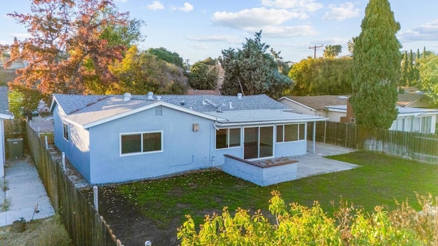 rear view of property featuring a sunroom, a patio, and a lawn