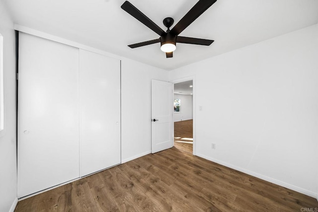 unfurnished bedroom with dark wood-type flooring, a closet, and ceiling fan