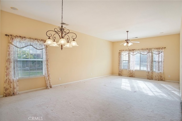 carpeted spare room featuring ceiling fan with notable chandelier