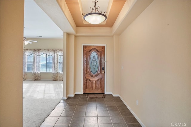 carpeted entryway featuring a tray ceiling and ceiling fan