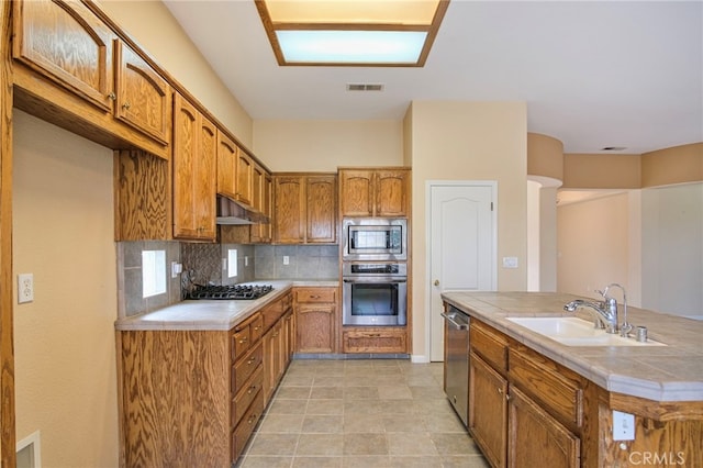 kitchen with sink, backsplash, tile counters, and appliances with stainless steel finishes