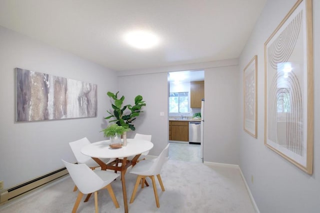 dining room featuring light carpet, a baseboard heating unit, and sink