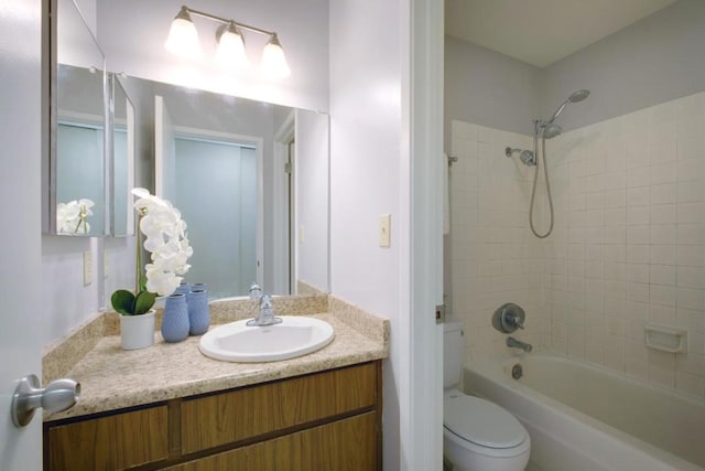 full bathroom featuring tiled shower / bath, vanity, and toilet